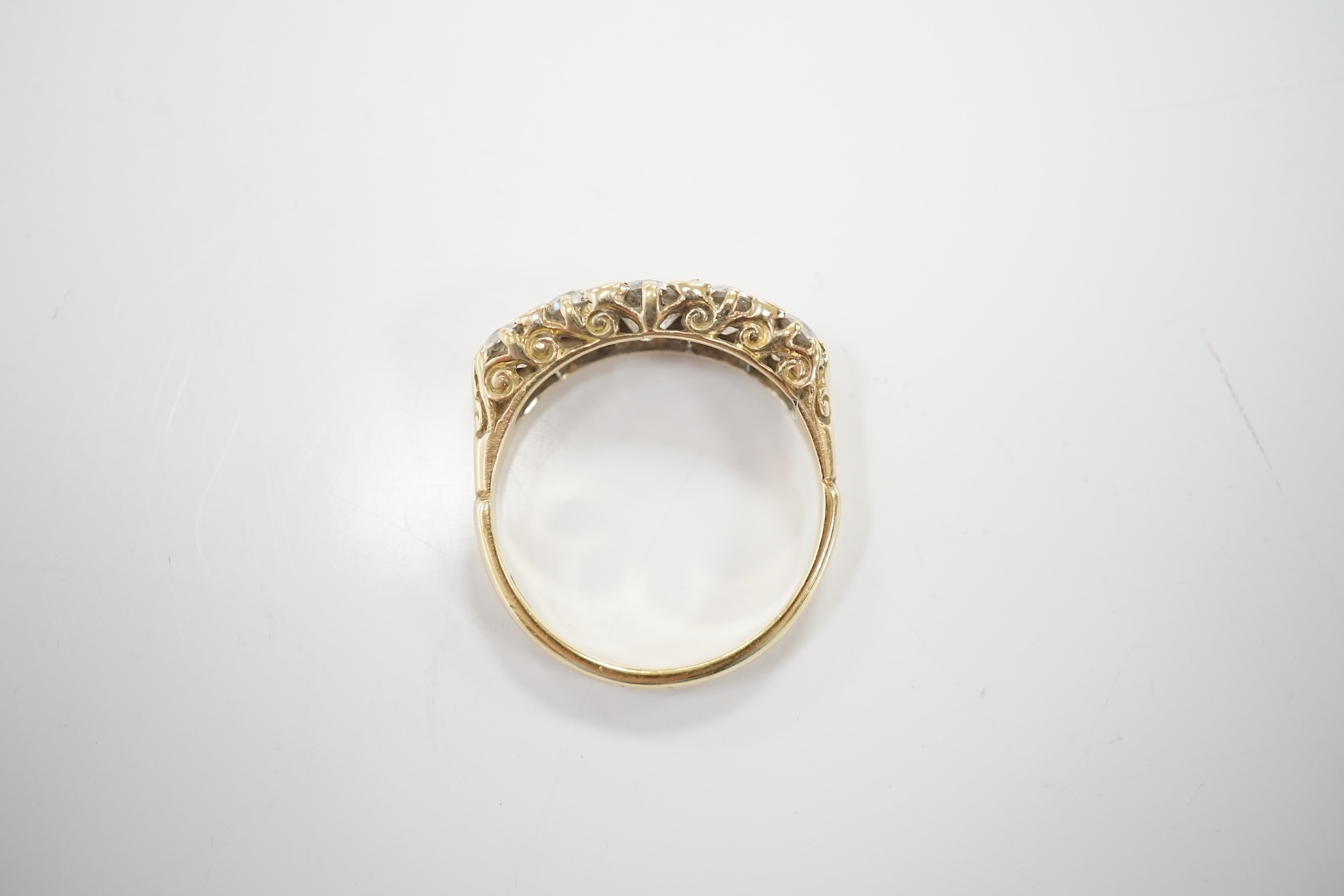 An early 20th century 18ct and graduated five stone diamond set half hoop ring, with rose cut diamond set spacers, size Q/R, gross weight 4 grams. Condition - poor to fair